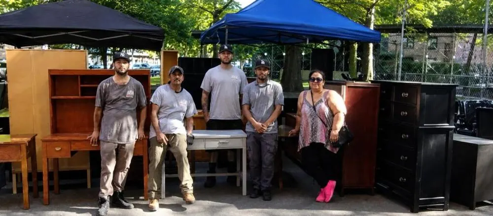 Repurposed Life volunteers standing with donated dressers and tables at a community event
